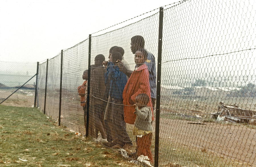 Frontiers within frontiers. Children behind fence that separates them from the white community near Johannesburg. 1/Jan/1973. UN Photo/Pendl. www.unmultimedia.org/photo/